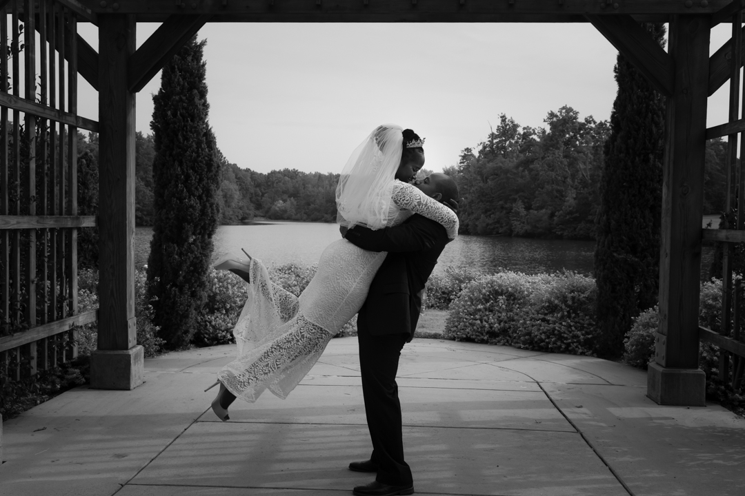 Dwight embraces Diamond outside, lifting her up off her heels, in a grayscale wedding photo